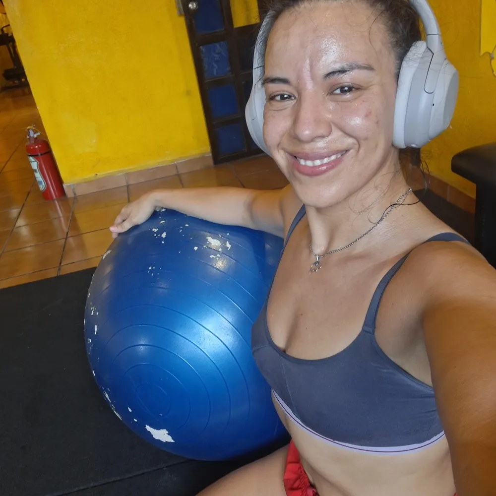 Gal Dorado resting with a stability ball between sets, headphones on