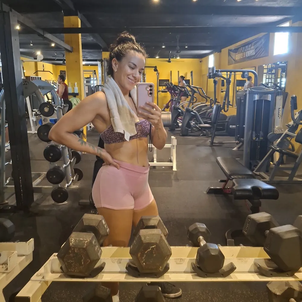 Gal Dorado with a towel over her shoulders at the dumbbell rack