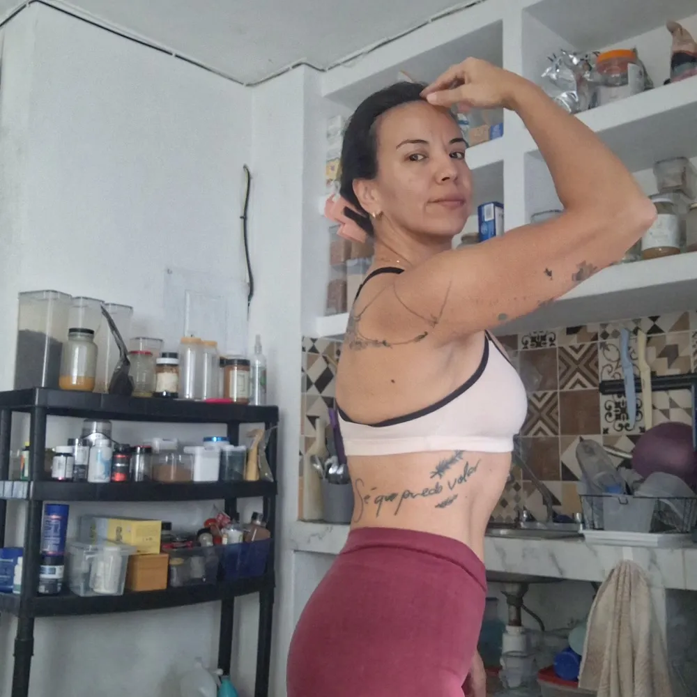 Gal Dorado flexing her bicep at home, the words 'Sé que puedo volar' tattooed along her ribs
