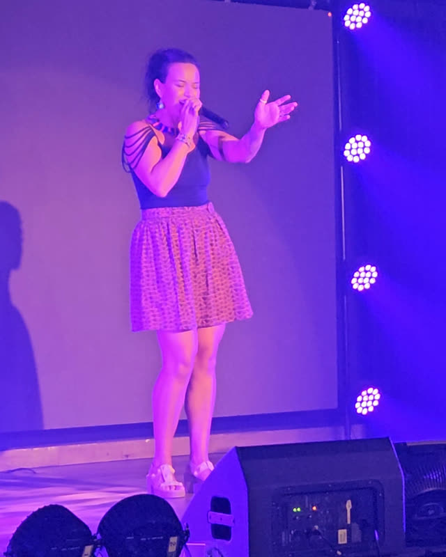 Gal Dorado singing live on stage, microphone in hand, under stage lights in Puerto Vallarta