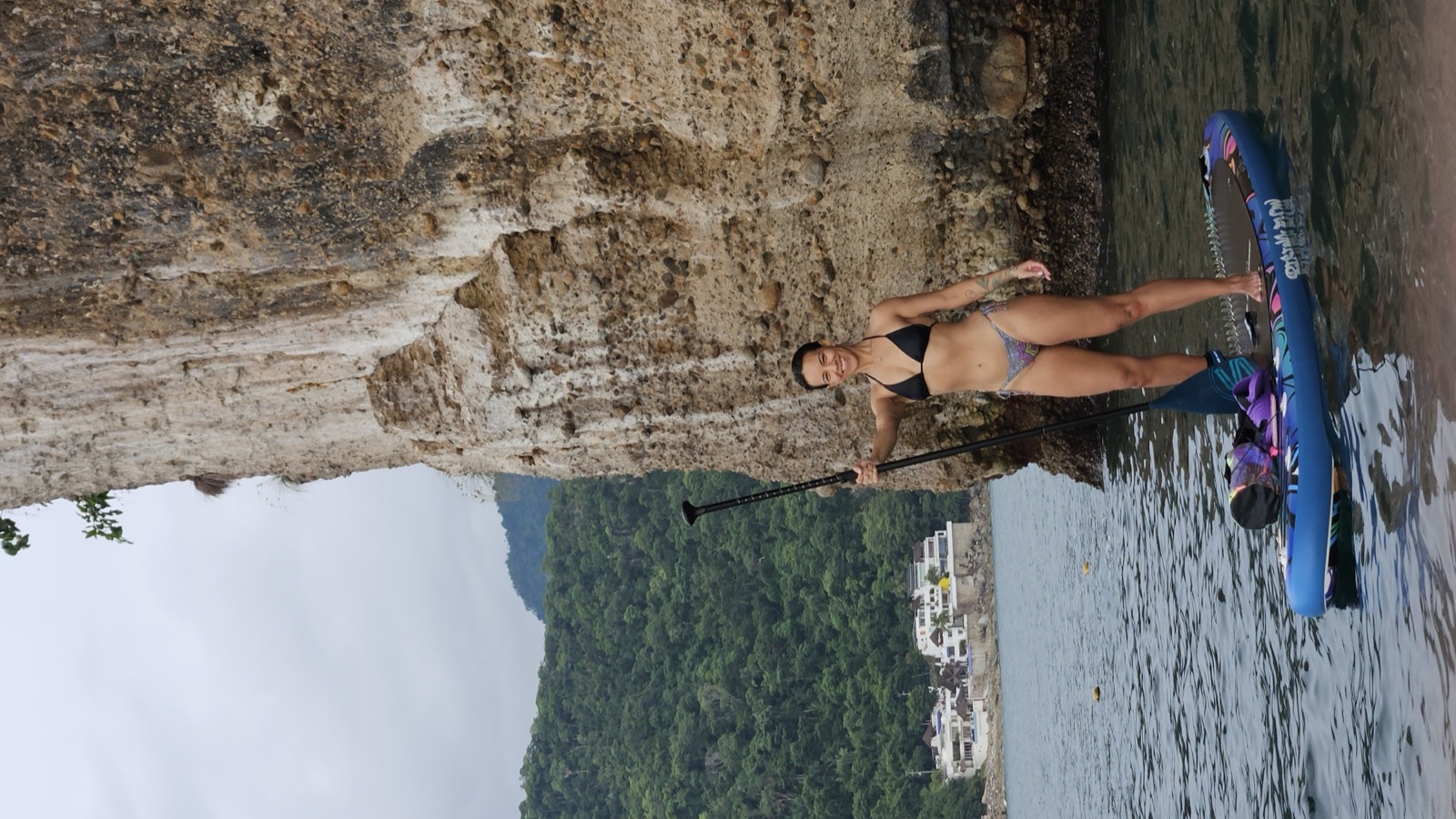 Gal Dorado standing on a paddleboard on the water beneath the cliffs of Bahía de Banderas